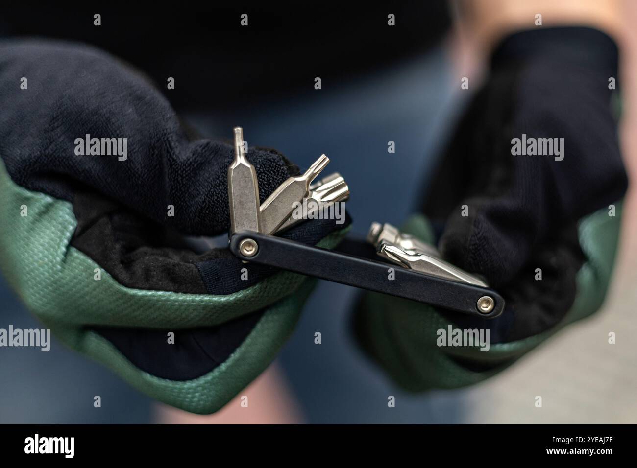 Primo piano di una mano con i guanti che regge un attrezzo multiuso per bicicletta Foto Stock