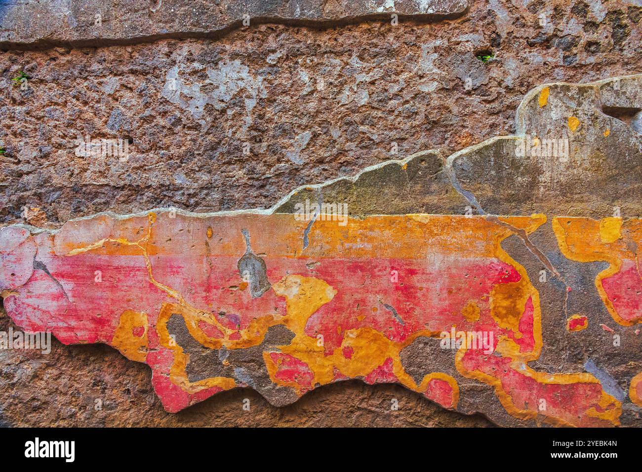 Una superficie murale vibrante e testurizzata caratterizzata da fantasie e disegni colorati e intricati di Pompei Foto Stock