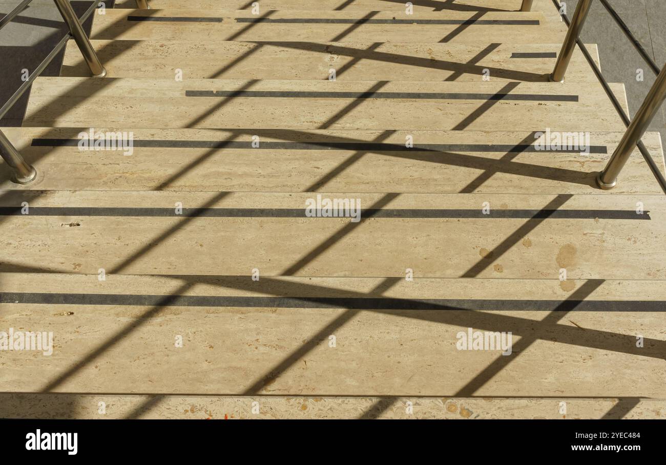 Una scala illuminata dal sole crea uno schema ipnotico di ombre e luci, mostrando caratteristiche architettoniche uniche. Foto Stock