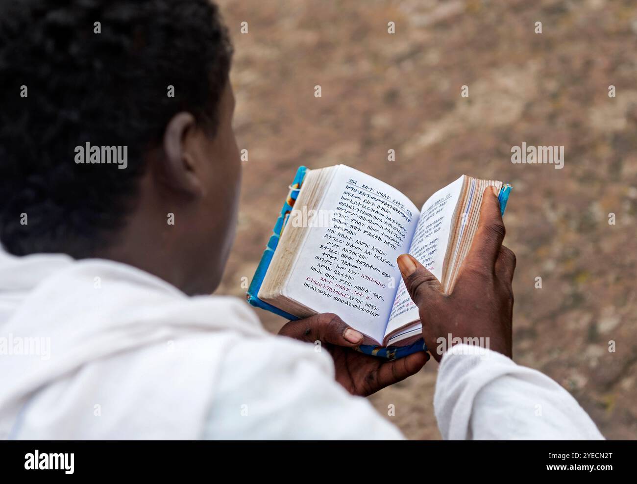 Giovane che legge il suo libro di preghiere scritto in lingua amarica la domenica mattina. Lalibela, Etiopia Foto Stock