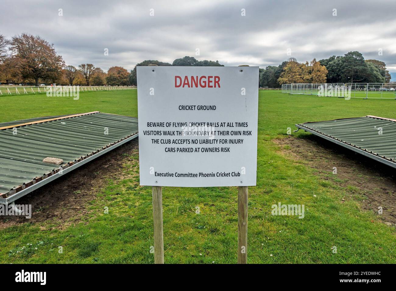 Cartello segnaletico al Phoenix Cricket Club di Phoenix Park, Dublino, Irlanda, che avvisa i visitatori del pericolo di volare palle da cricket e camminare al loro fianco Foto Stock