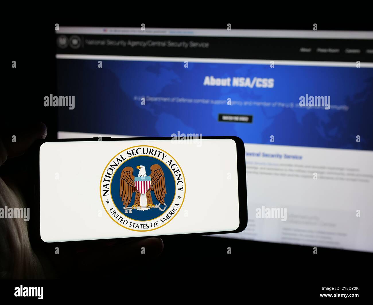 Persona che possiede un telefono cellulare con il logo dell'Agenzia nazionale per la sicurezza (NSA) sullo schermo davanti alla pagina Web. Mettere a fuoco il display del telefono. Foto Stock