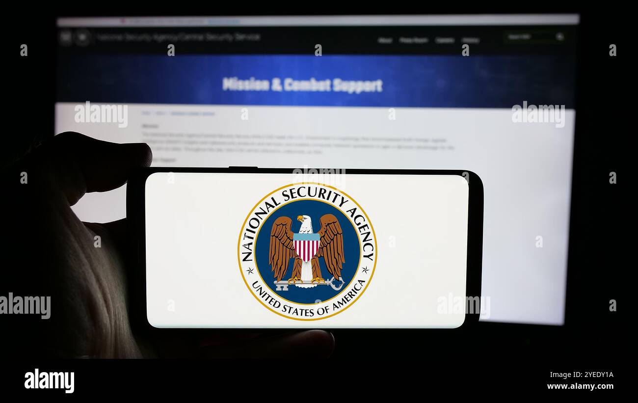 Persona che detiene un cellulare con il logo dell'Agenzia nazionale per la sicurezza (NSA) sullo schermo davanti alla pagina web. Mettere a fuoco il display del telefono. Foto Stock