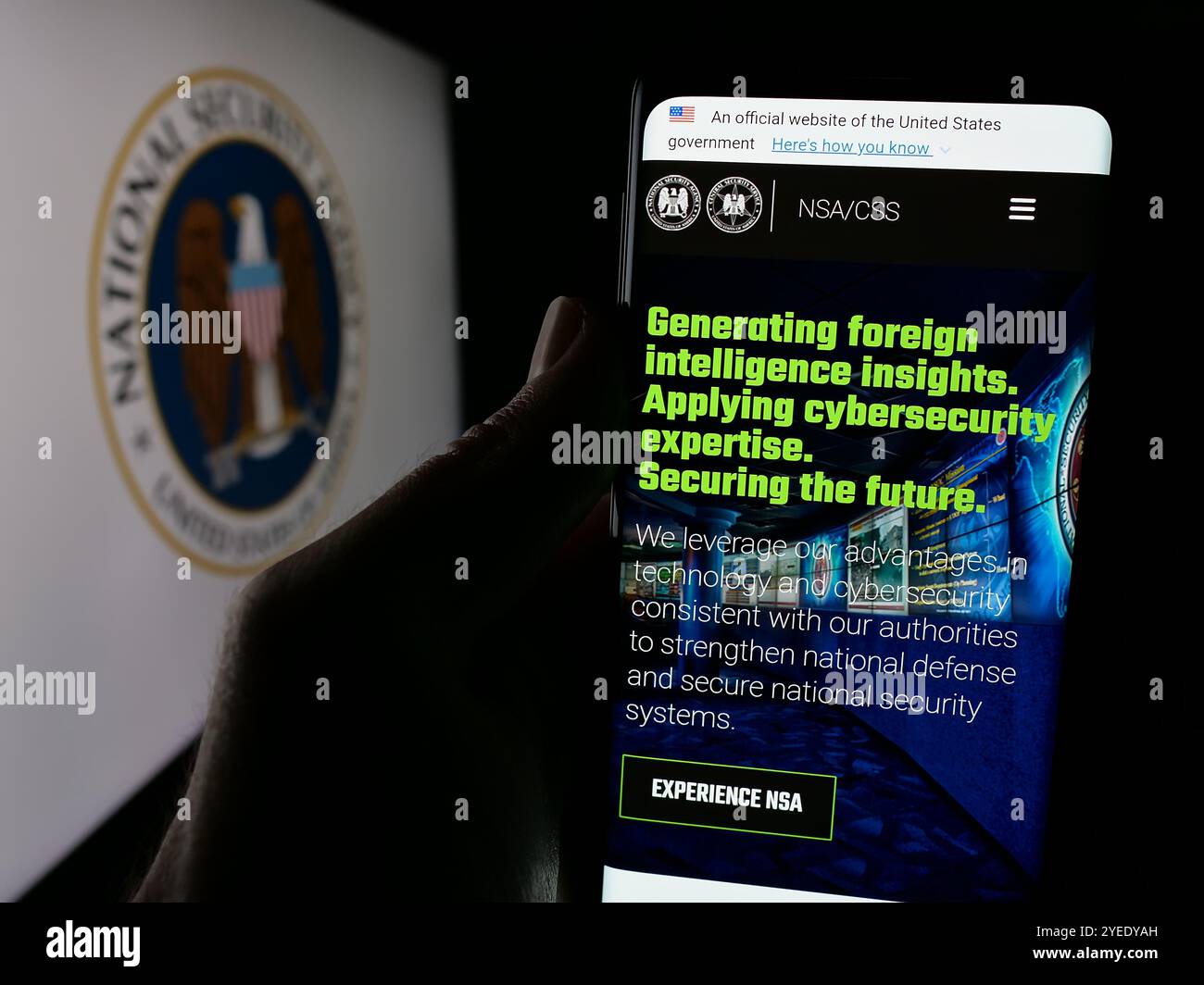 Persona che detiene un cellulare con la pagina web dell'Agenzia nazionale di sicurezza (NSA) sullo schermo davanti al logo. Messa a fuoco al centro del display del telefono. Foto Stock