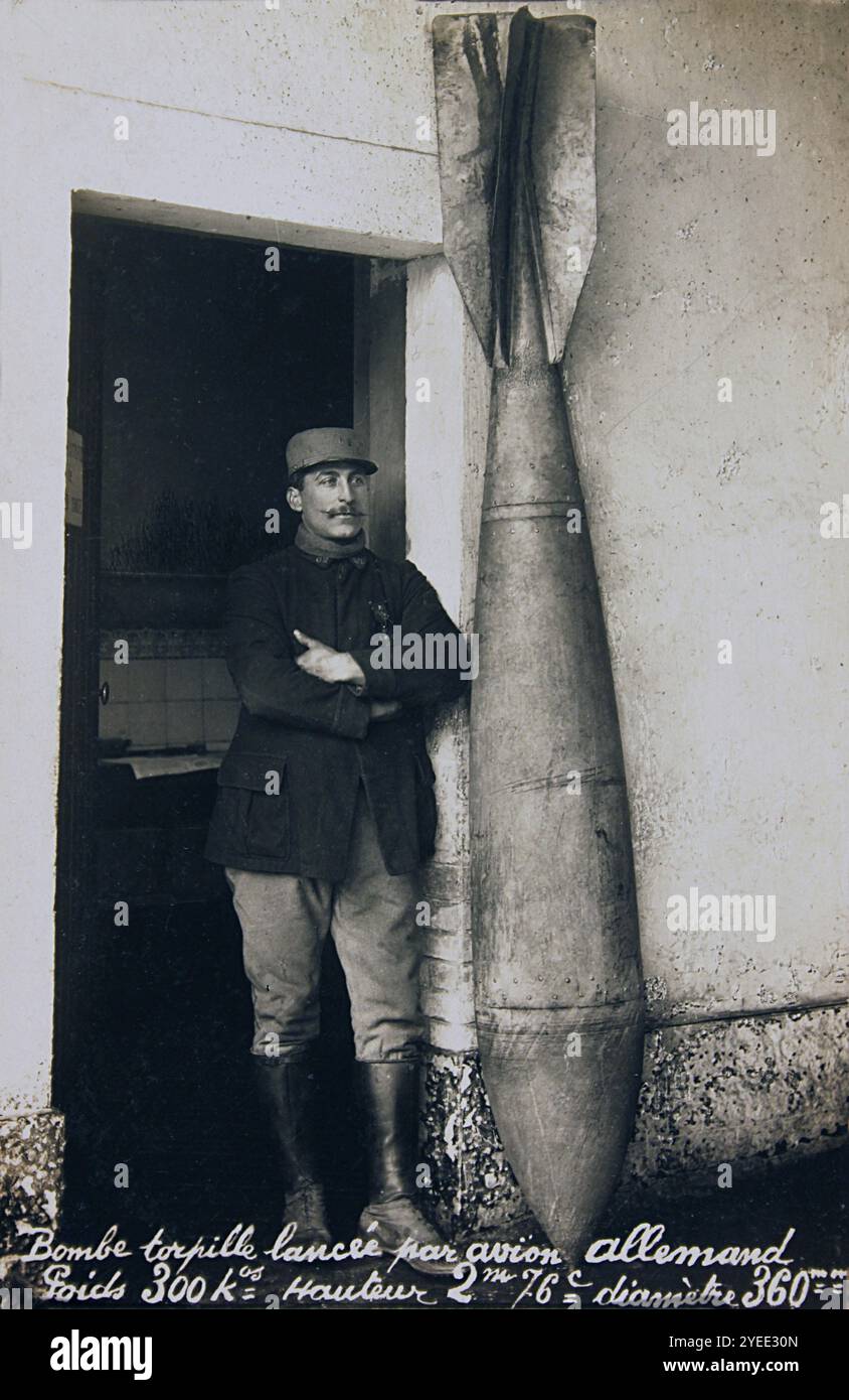 Cartolina d'epoca che mostra l'ufficiale francese della prima guerra mondiale in piedi accanto a una bomba tedesca inesplosa da 300 chili lanciata in un bombardamento aereo di linee francesi. Foto Stock