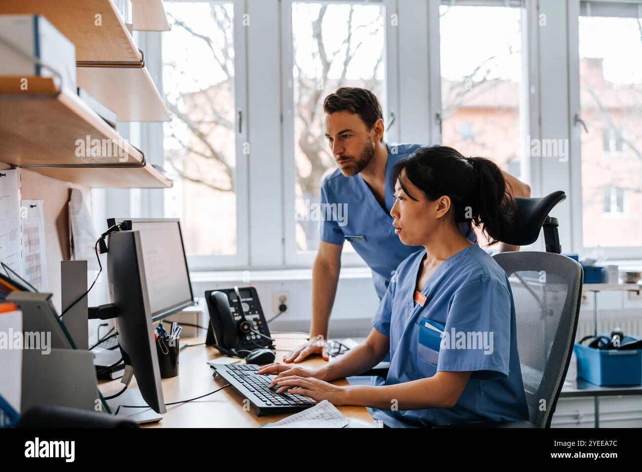 Professionisti medici maschili e femminili che lavorano su computer in clinica Foto Stock