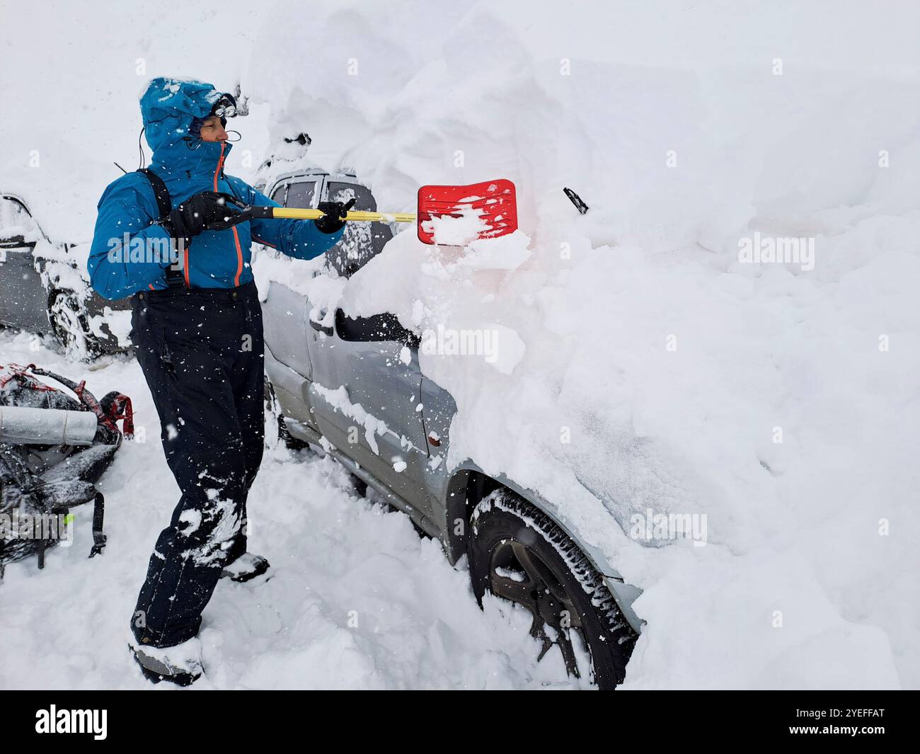 Viaggiando in montagna in inverno: Donna usa una pala per rimuovere la neve che copre completamente il suo veicolo, a Mendoza, Argentina. Foto Stock