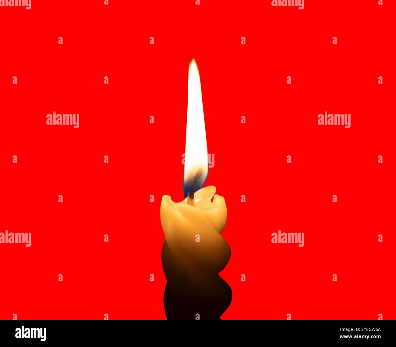 Una singola fiamma di candela bruciata o una luce accesa su una piccola candela bianca a spirale è isolata su sfondo rosso con percorso di ritaglio. Foto Stock