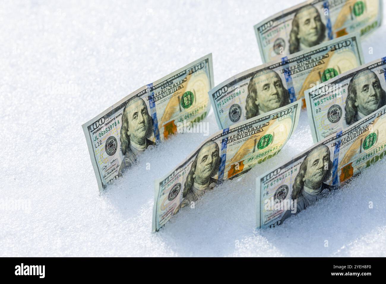 banconote in dollari americani in piedi sul loro fianco sulla superficie della neve nelle soleggiate giornate invernali Foto Stock