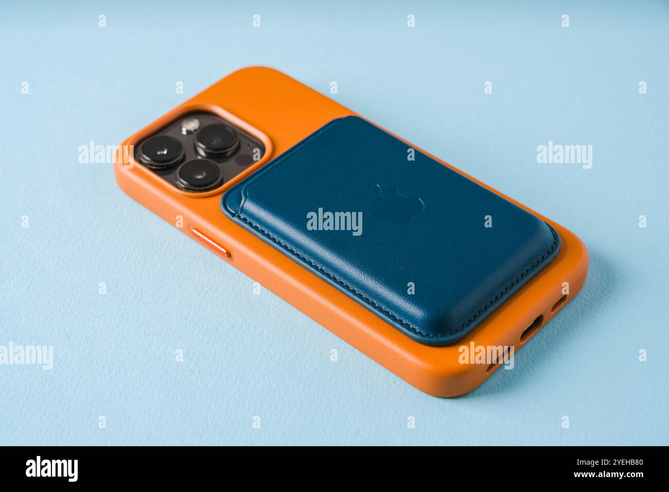 Antalya, Turchia - 28 ottobre 2024: Custodia Magsafe marrone e portafoglio Magsafe attaccati all'iPhone 13 Pro su sfondo blu Foto Stock