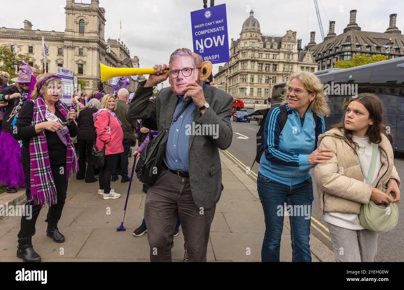 Westminster, Londra, Regno Unito, ottobre 30 2024, dimostrazione WASPI in occasione del budget Day, con un uomo che indossa una maschera e due membri del pubblico che sembrano sconcertati Foto Stock