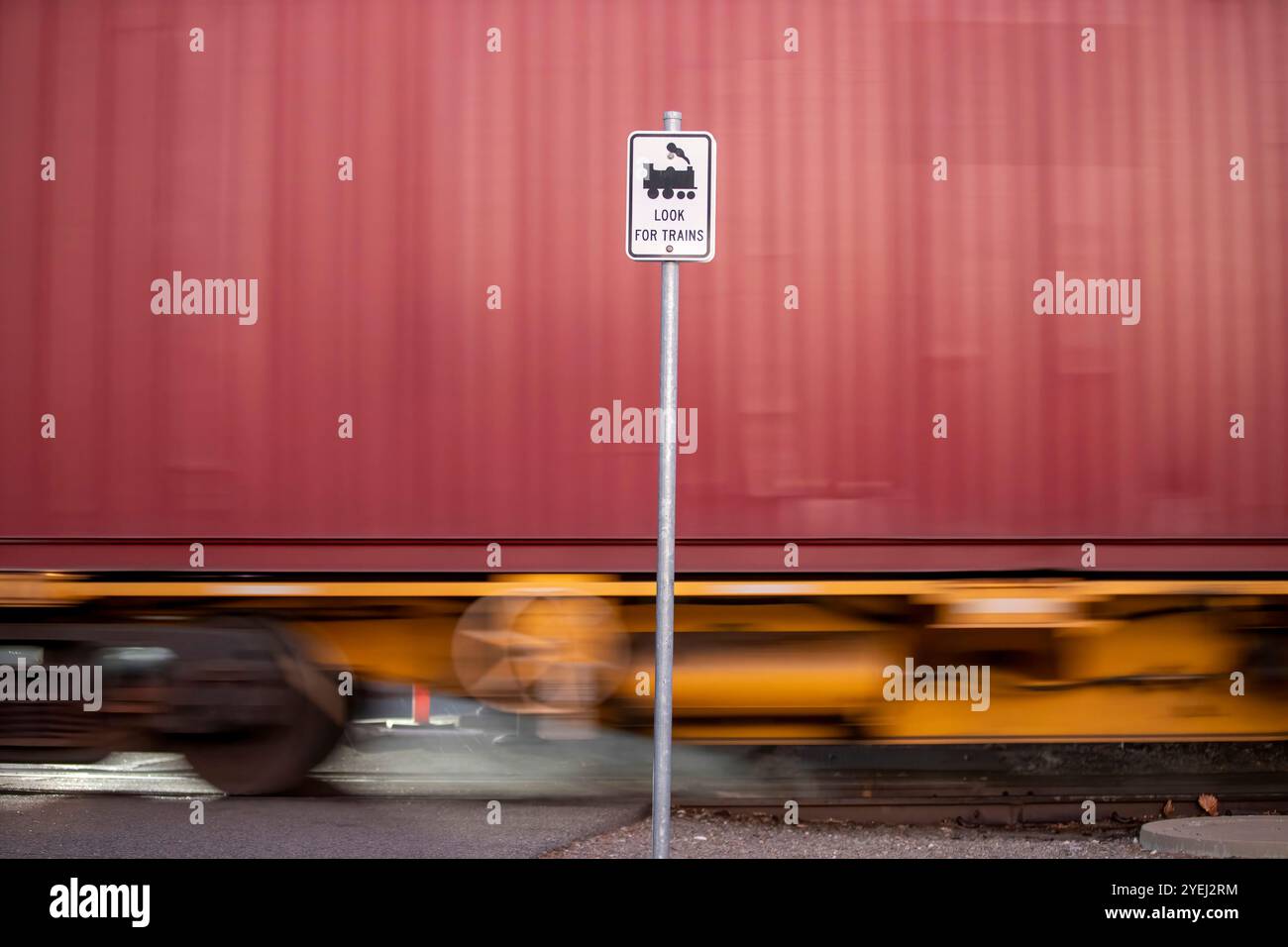 Questa fotografia mostra un cartello "Cerca treni" con una messa a fuoco nitida, con un treno rosso sfocato che passa sullo sfondo, catturando il senso di velocità Foto Stock