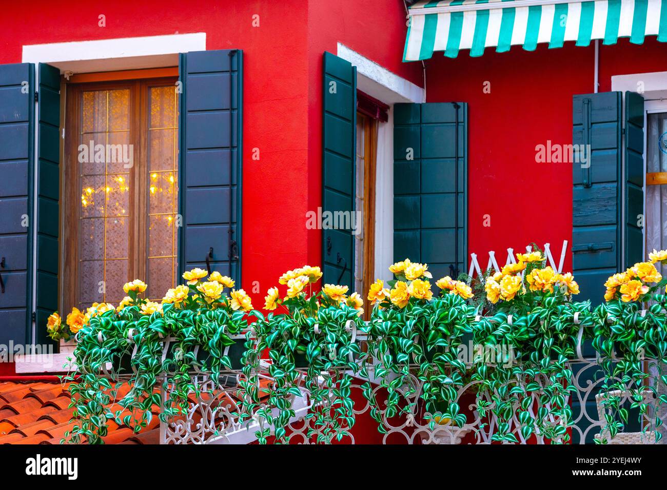 L'isola di Burano, finestre con fiori, colorata architettura di case rosse, strada nella famosa isola vicino a Venezia. Concetto di viaggio e vacanza Foto Stock