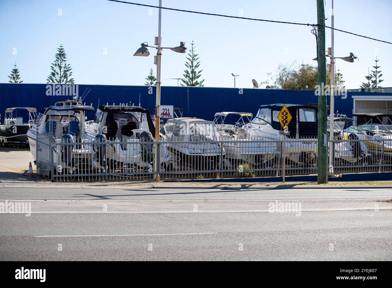 Una concessionaria di barche che espone una varietà di piccole imbarcazioni, parcheggiate dietro una recinzione metallica. Foto Stock