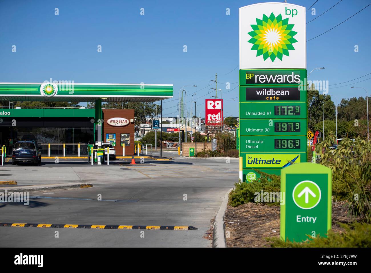 Ingresso al distributore di benzina BP con un cartello che mostra i prezzi correnti del carburante, un Wild Bean Café e il marchio della stazione. Foto Stock