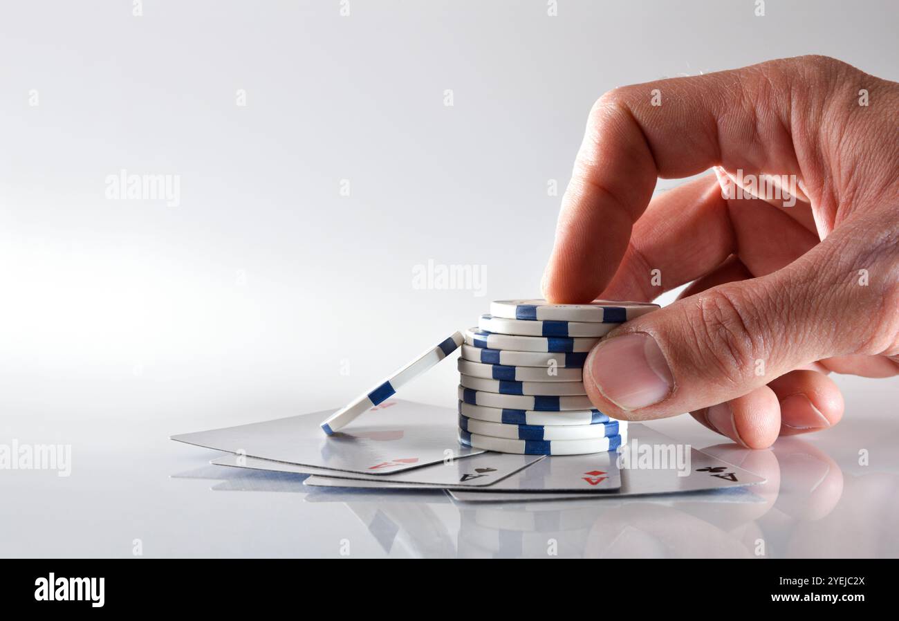 Scommesse manuali con chip su quattro assi riflesse su un tavolo bianco e uno sfondo bianco isolato. Vista frontale. Foto Stock