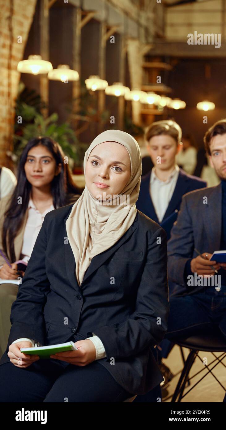 Gruppo multirazziale di uomini d'affari che ascoltano attentamente durante i seminari in un moderno spazio di lavoro. Formazione aziendale in un ambiente dinamico. Foto Stock