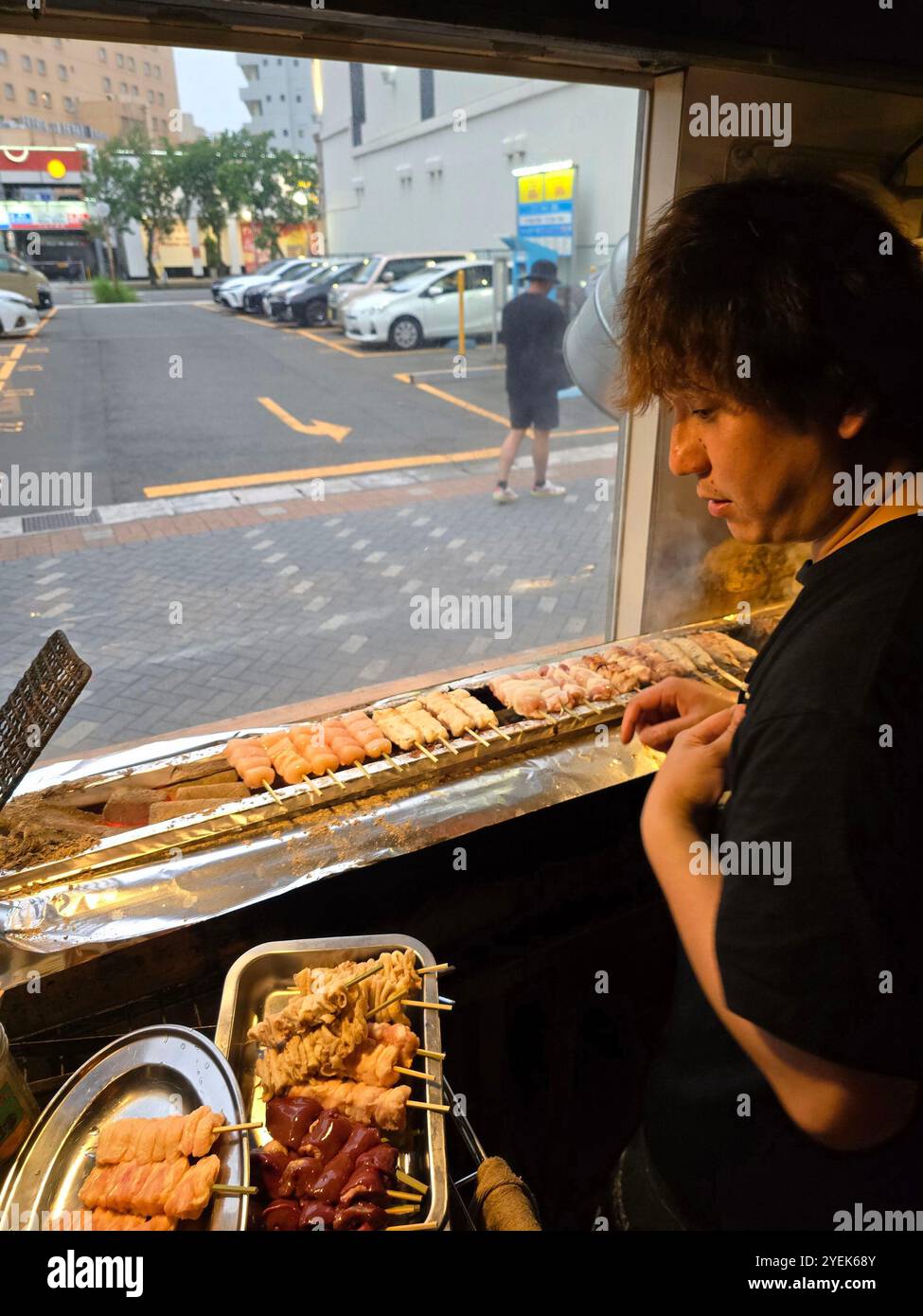 Un giovane giapponese che grigia spiedini al ristorante Washio Yakitori Izakaya a Chuocho, Kagoshima, Giappone. Foto Stock