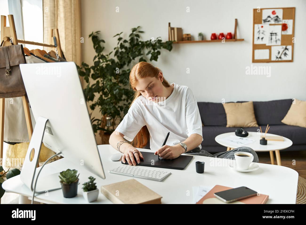 Un individuo creativo si concentra intensamente sull'arte digitale, circondato da un ambiente tranquillo e verde. Foto Stock