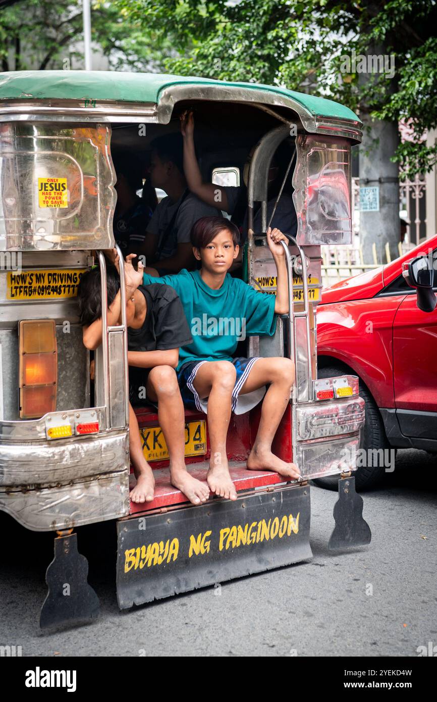 Giovani ragazzi filippini si siedono sul retro di un Jeepney a Manila, nelle Filippine. Foto Stock