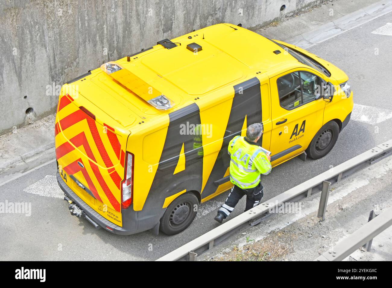Stesso incidente Alamy 2XRWMM1 AA meccanico cammina fino al furgone completato assistere l'automobilista in un'auto in avaria sotto la copertura del ponte autostradale Essex Inghilterra Regno Unito Foto Stock