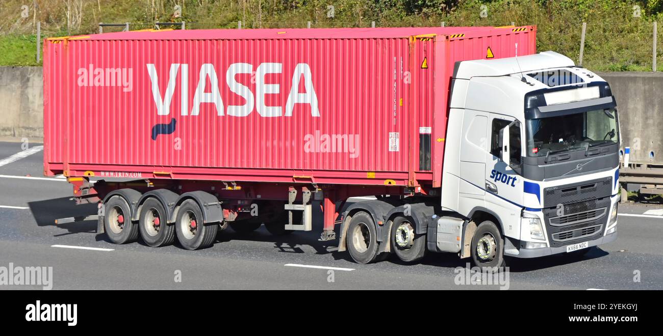 Contenitore di spedizione in acciaio rosso VIASEA su semirimorchio articolato a scheletro trainato da autocarro Volvo hgv bianco sulla strada autostradale M25 Essex Inghilterra Regno Unito Foto Stock