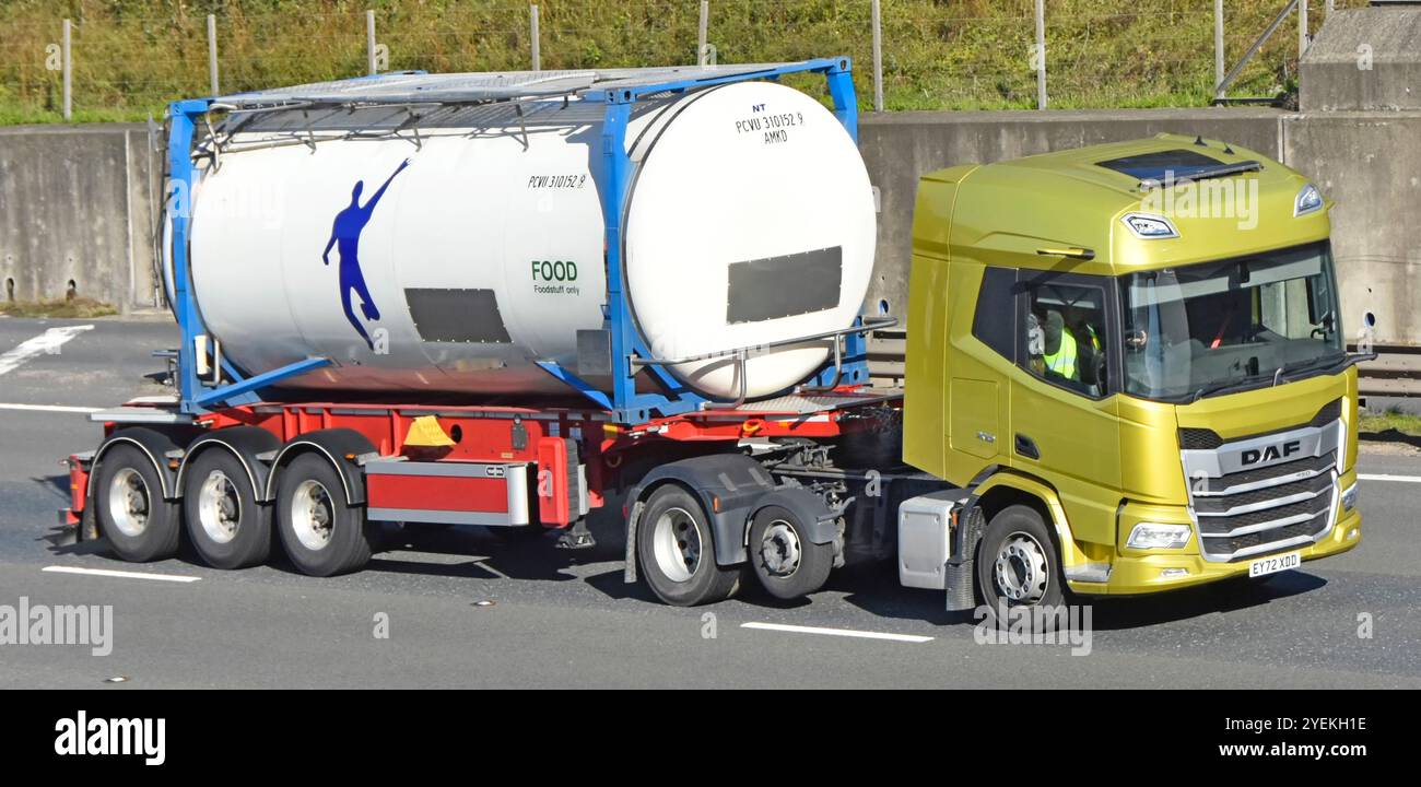 Veicolo industriale hgv a marchio DAF di colore giallo per il traino di rimorchi scheletrici con serbatoio per alimenti intermodale per l'azionamento di cilindri autostradali M25 Inghilterra Regno Unito Foto Stock