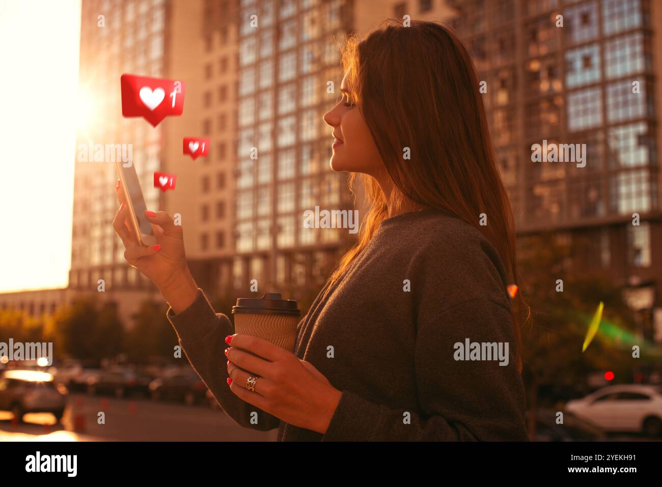 Giovane donna felice che controlla i social network sul suo smartphone mentre è in movimento in città al tramonto Foto Stock