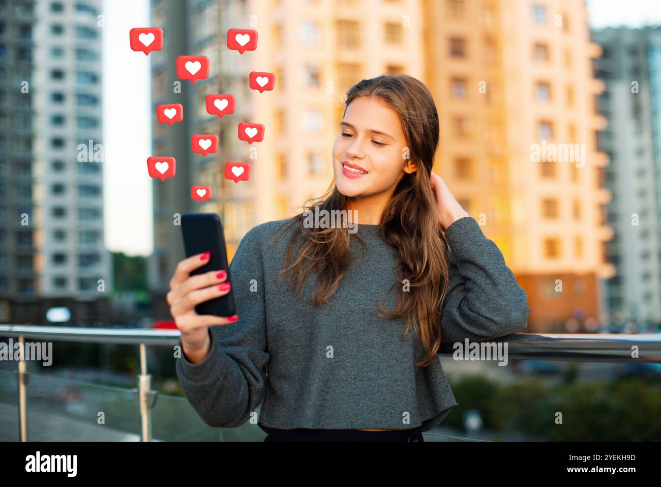 La giovane donna urbana riceve i mi piace sui social media, utilizzando l'app di incontri online sugli smartphone sullo sfondo della città Foto Stock