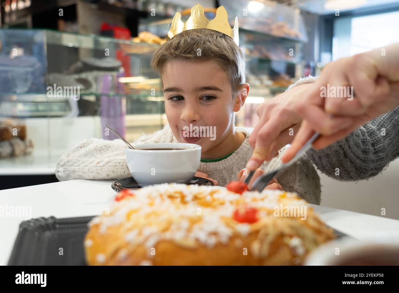 Niño el día de Reyes tomando Chocolate caliente y roscón con su madre en una cafetería. 6 de enero. Tradición Española Foto Stock