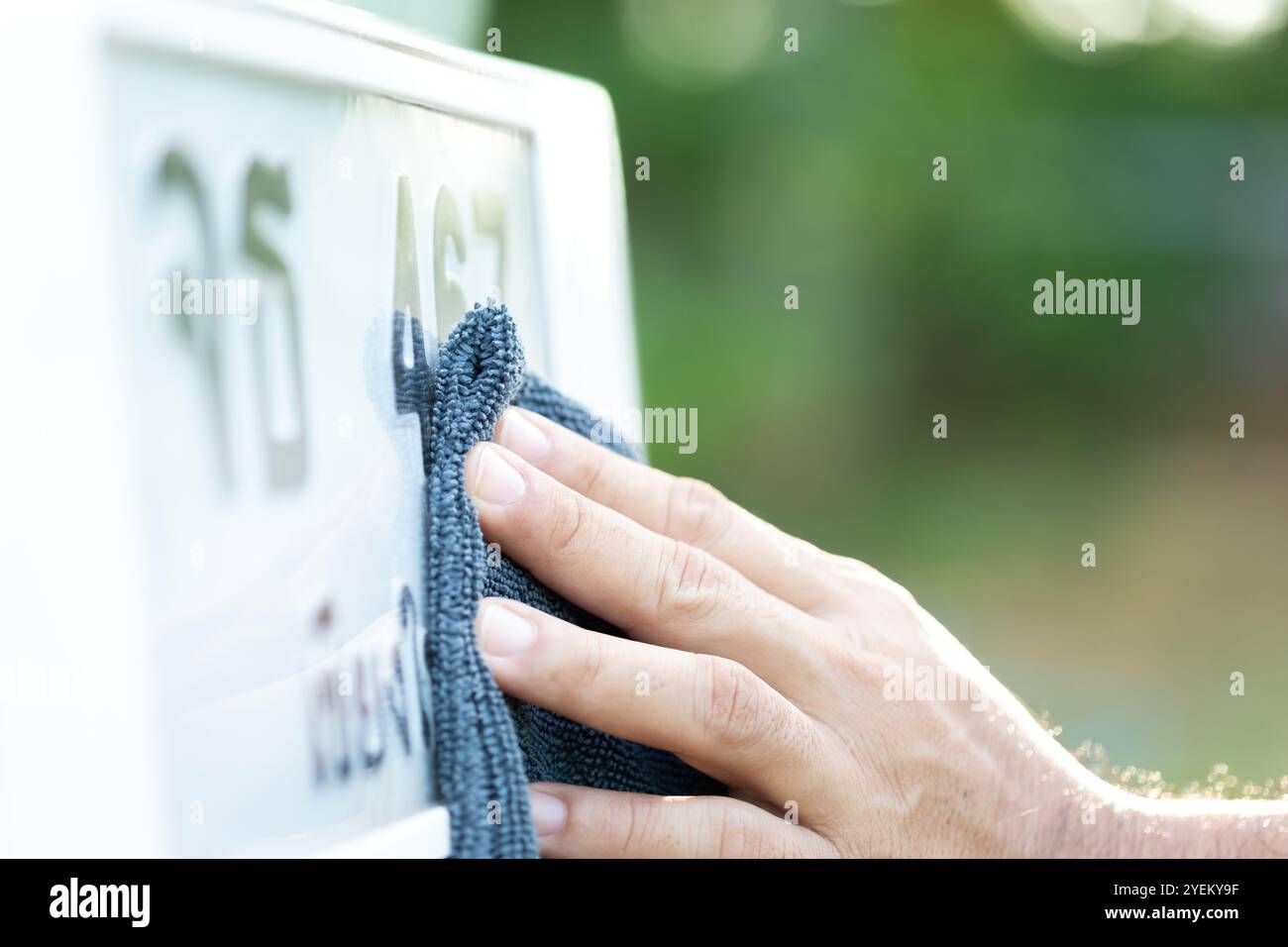 Il proprietario dell'auto pulisce accuratamente la targa, riflettendo le credenze thailandesi nei numeri fortunati sulle targhe dei veicoli e l'attenzione prestata alla manutenzione Foto Stock