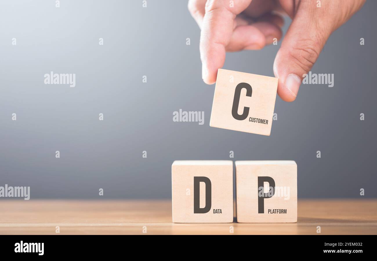 Sistemare a mano blocchi di legno con le lettere C, D e P su un tavolo. Rappresenta il concetto di creazione di una piattaforma dati per i clienti, sottolineando l'impulso Foto Stock