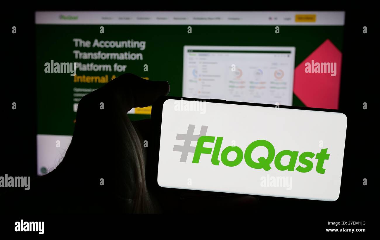 Persona che possiede un telefono cellulare con il logo della società americana di software per la contabilità FloQast Inc. Sullo schermo davanti alla pagina Web. Mettere a fuoco il display del telefono. Foto Stock