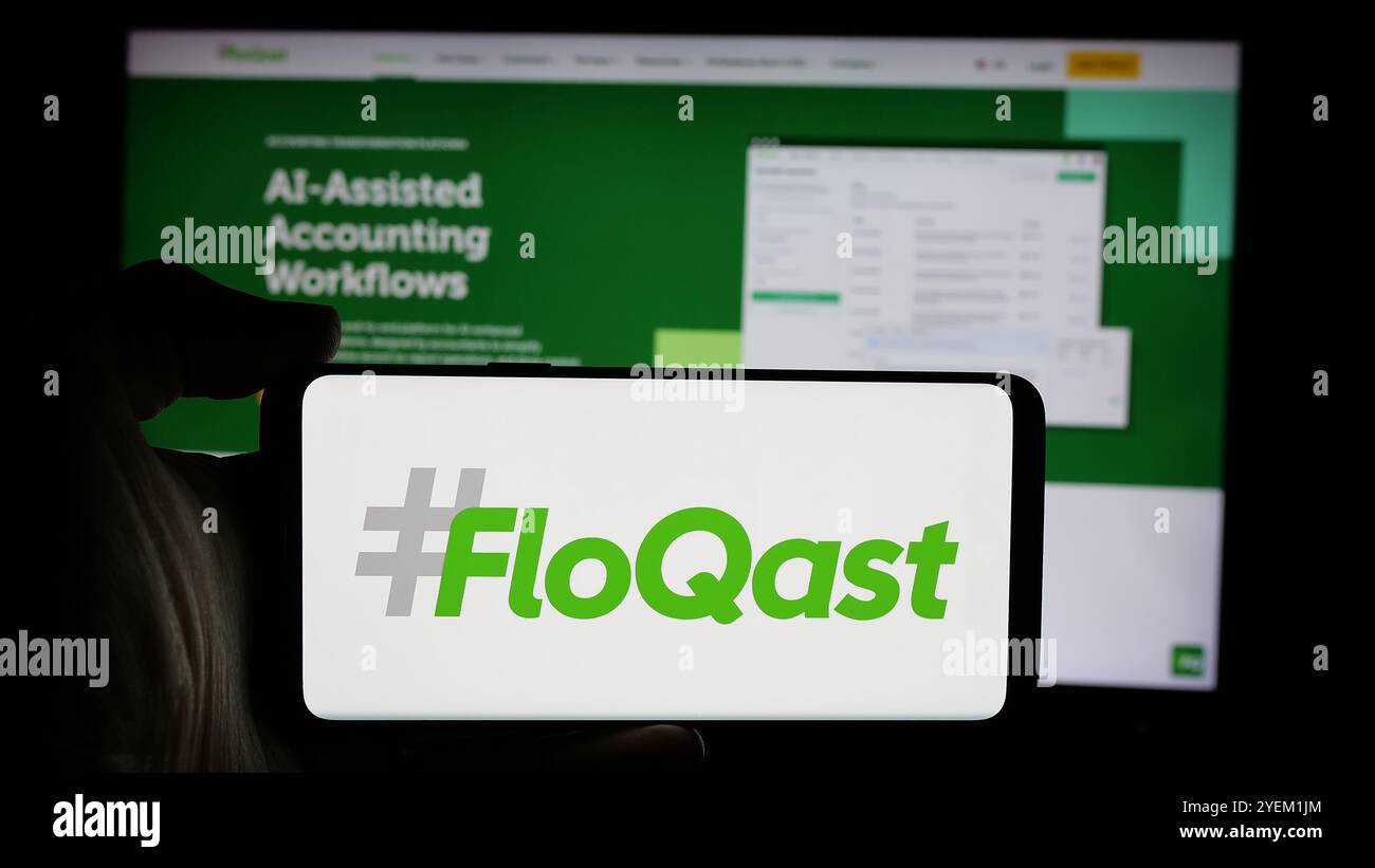 Persona che detiene un cellulare con il logo della società di software contabile statunitense FloQast Inc. Sullo schermo di fronte alla pagina Web aziendale. Mettere a fuoco il display del telefono. Foto Stock