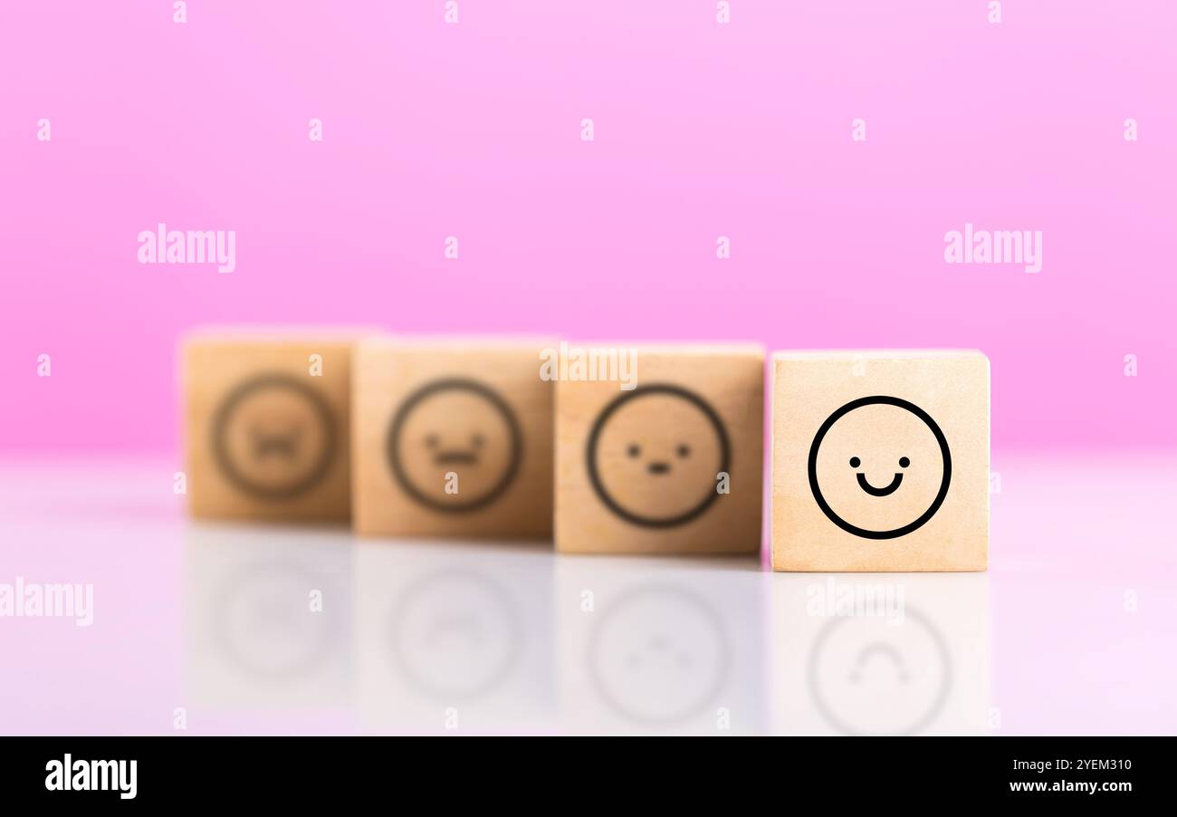 Blocchi di legno che mostrano una serie di adesivi sorridenti disposti da una faccia felice a una faccia triste. L'immagine simboleggia lo spettro delle emozioni, malato Foto Stock
