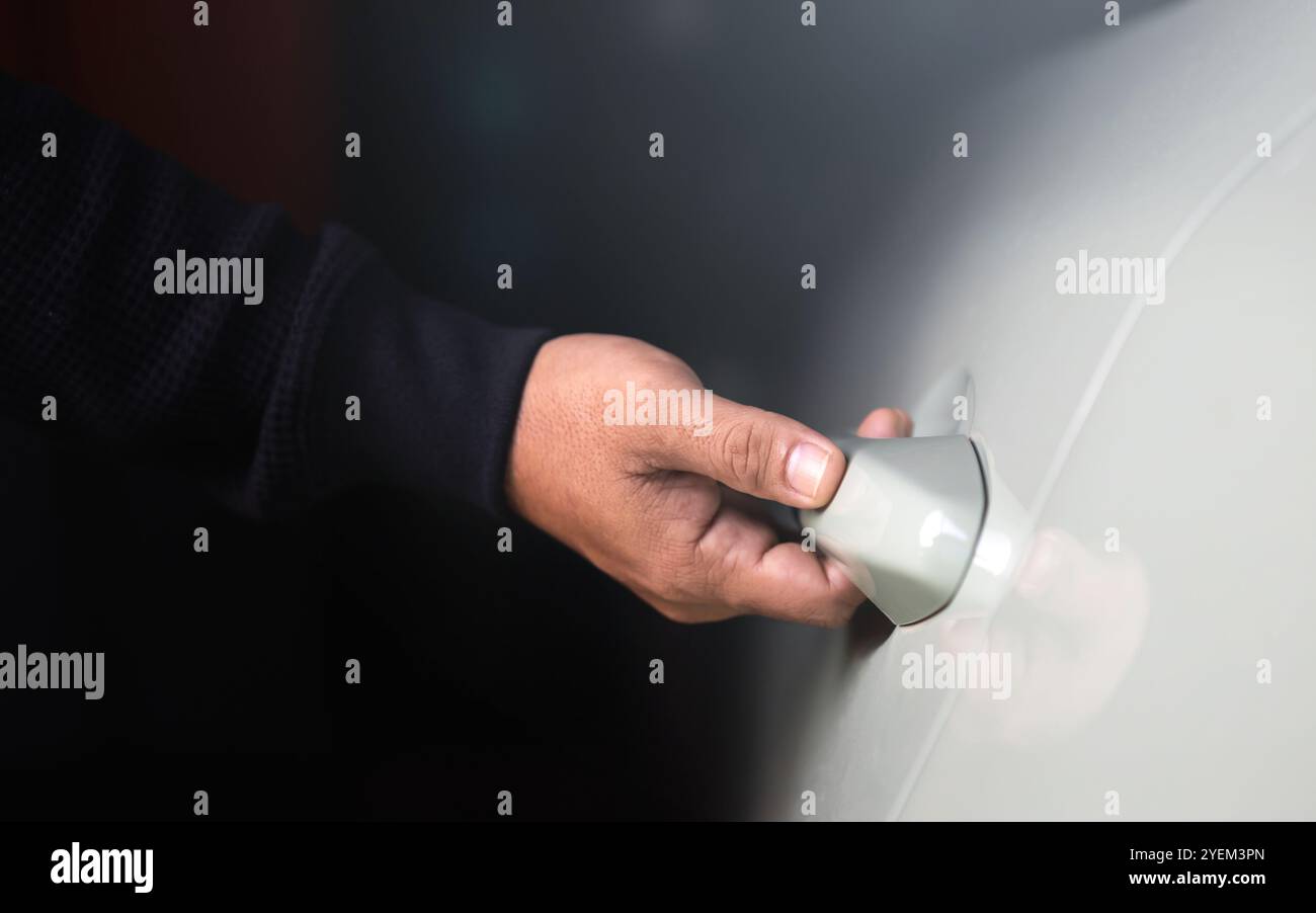 La mano di un uomo che si avvicina per aprire la porta di un'auto. L'immagine rappresenta il concetto di utilizzo del veicolo, sottolineando l'azione quotidiana di accesso e utilizzo di una CA Foto Stock