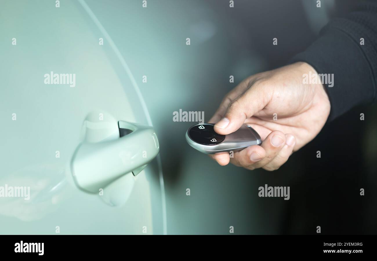 Mano di un uomo che tiene in mano un telecomando per sbloccare il veicolo. L'immagine rappresenta il concetto di utilizzo di un telecomando per auto, evidenziando il ruolo della batteria remota Foto Stock