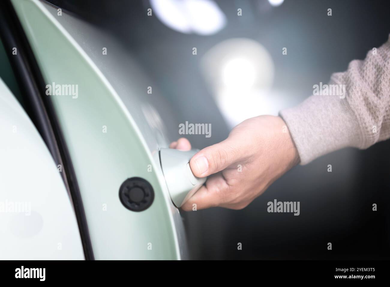 La mano di un uomo che si avvicina per aprire la porta di un'auto. L'immagine rappresenta il concetto di utilizzo del veicolo, sottolineando l'azione quotidiana di accesso e utilizzo di una CA Foto Stock