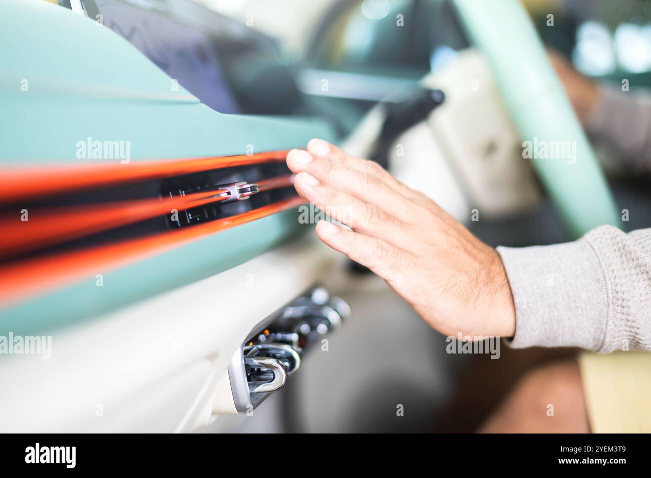 Il proprietario della vettura controlla l'impianto di climatizzazione rilevando l'aria fredda proveniente dalla bocchetta di ventilazione dopo che il veicolo è stato inondato. Concetto di manutenzione del veicolo, Foto Stock
