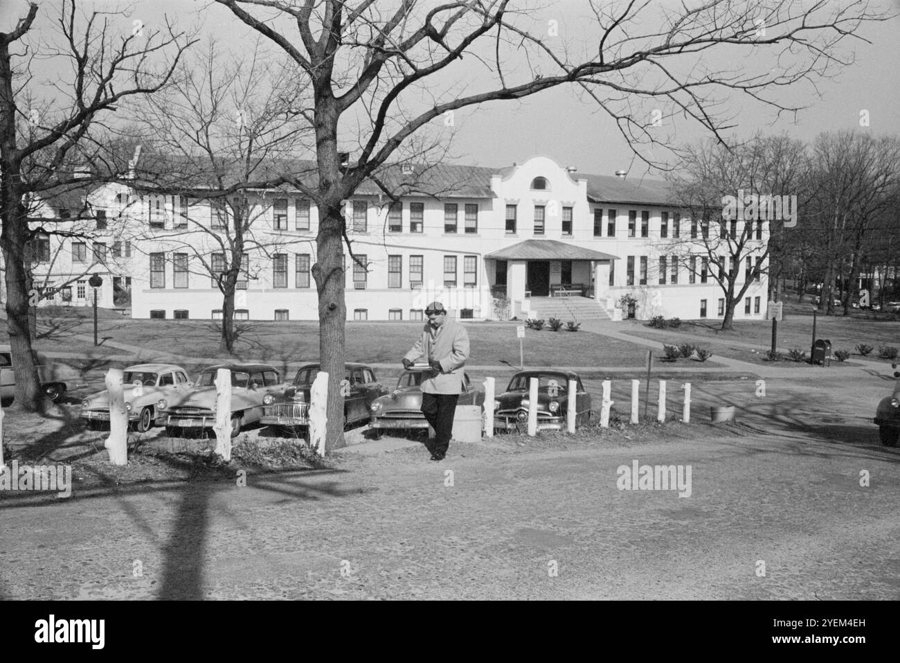 Uomo che cammina di fronte all'edificio amministrativo del Montgomery Junior College, Takoma Park, Maryland. STATI UNITI. Febbraio 1958 Foto Stock