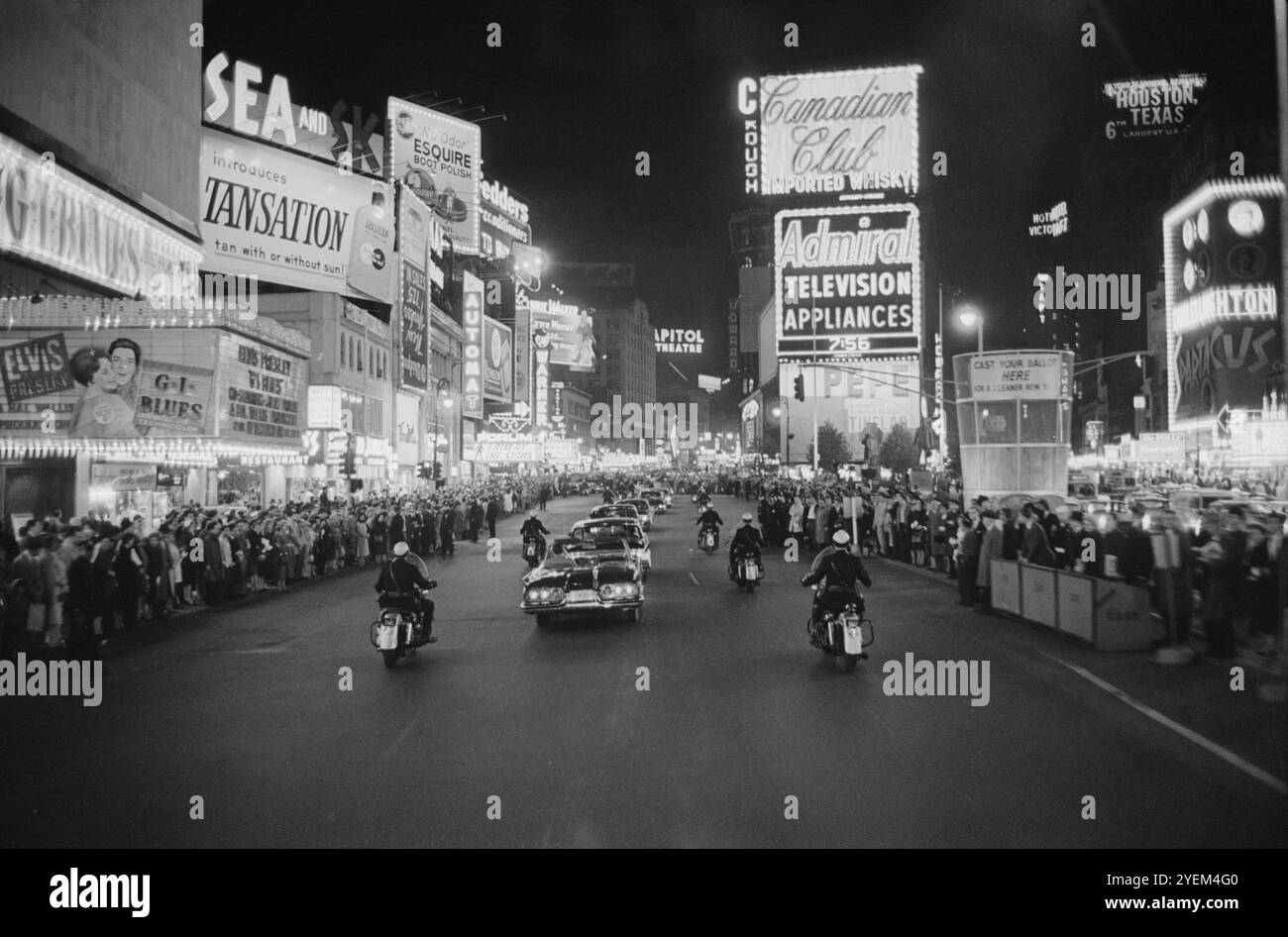 Un corteo con scorta della polizia motociclistica guida di notte da folle ed edifici con insegne al neon; probabilmente collegato a una manifestazione repubblicana al New York Coliseum, New York City. STATI UNITI. 2 novembre 1960 Foto Stock