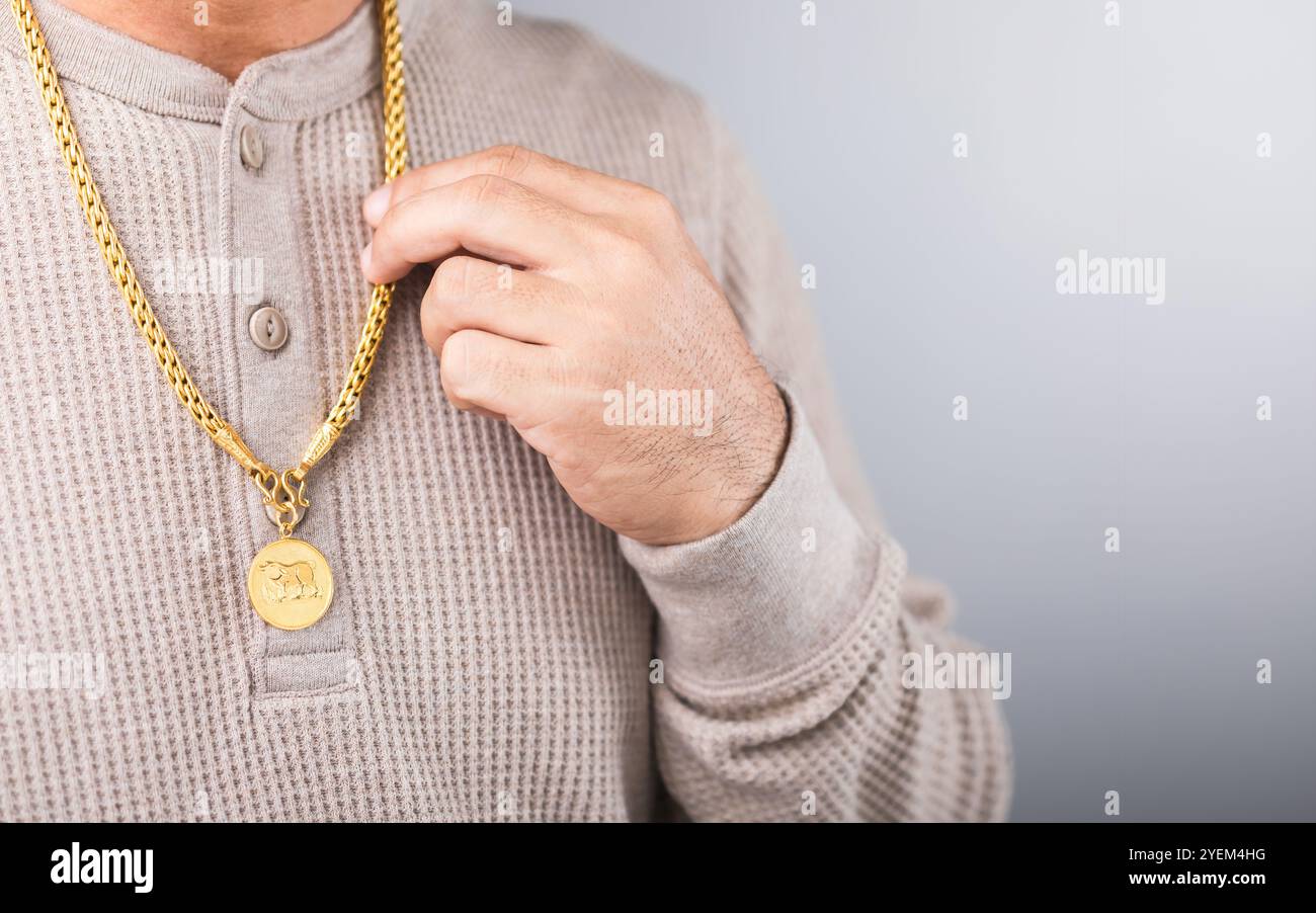 Primo piano di un uomo che indossa una collana d'oro, simboleggiando le speculazioni di mercato. Rappresenta il concetto di monitoraggio dei prezzi dell'oro, evidenziando la connessione Foto Stock