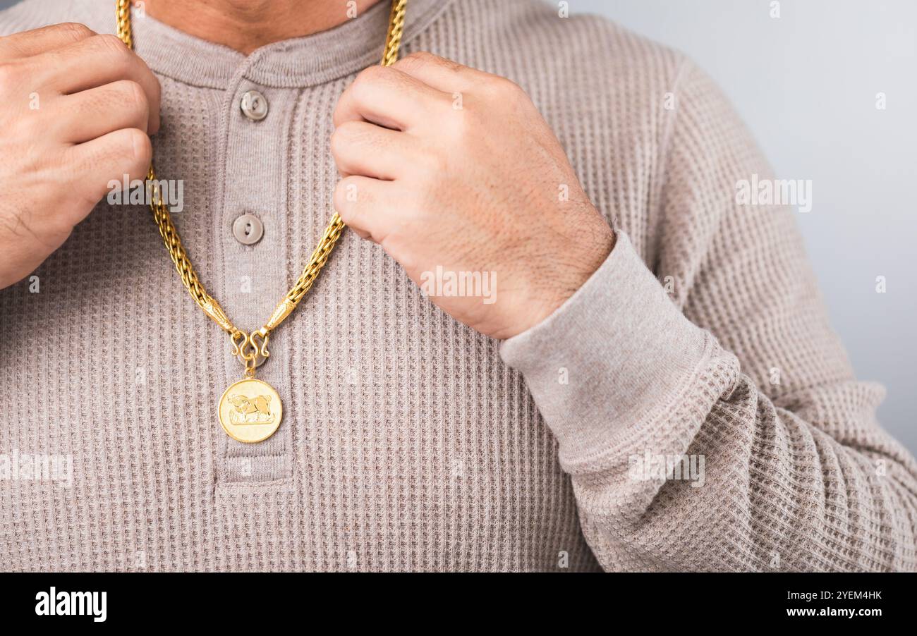 Primo piano di un uomo che indossa una collana d'oro, simboleggiando le speculazioni di mercato. Rappresenta il concetto di monitoraggio dei prezzi dell'oro, evidenziando la connessione Foto Stock