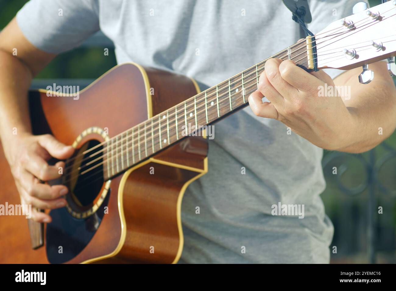 Un artista suona uno strumento musicale durante un concerto. Un primo piano dell'esecuzione della musica: Una chitarra e le mani che suonano sulle sue corde metal Foto Stock