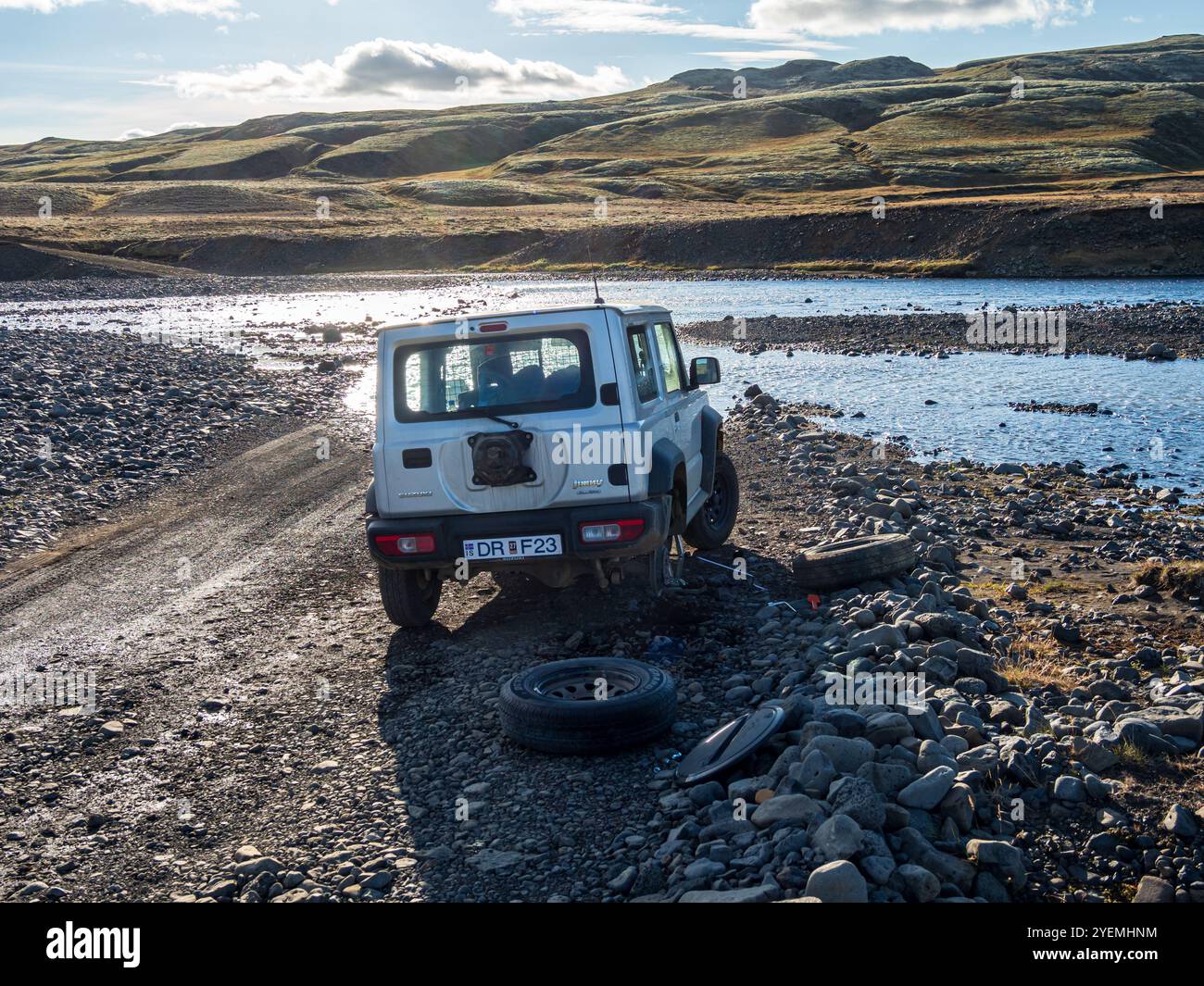 Auto 4x4 con pneumatico forato, cambio di pneumatico all'attraversamento del fiume sulla strada di montagna F206, strada per il cratere Laki o Lakagígar, altopiani interni dell'Islanda, su Foto Stock
