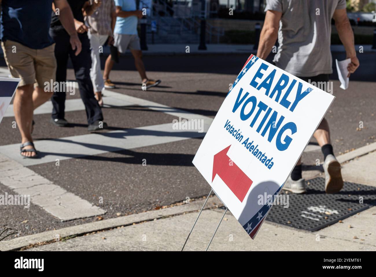 Manifesto di voto anticipato con persone irriconoscibili che camminano sulla strada pubblica. Voto anticipato per le elezioni del 2024 negli Stati Uniti Foto Stock