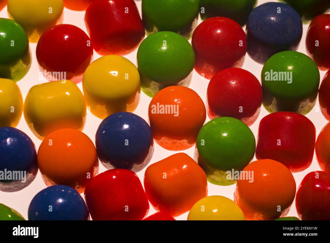 Caramelle colorate su sfondo bianco retroilluminato. Foto Stock