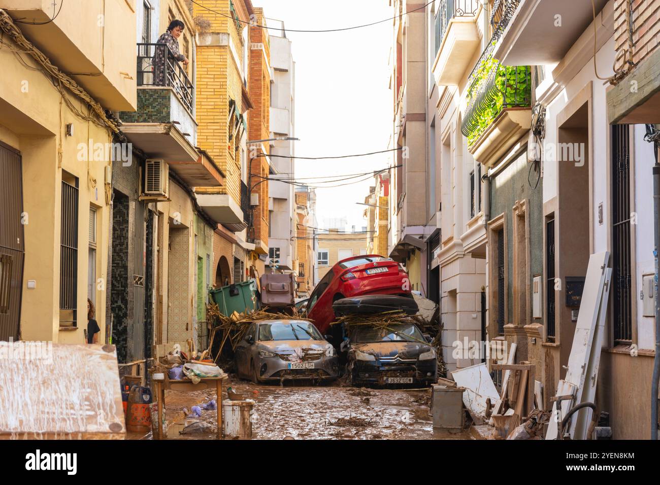 Catarroja, Valencia, Spagna. 31 ottobre 2024 - dopo la recente inondazione, una vicina guarda dal suo balcone con stupore lo stato della sua strada, Foto Stock