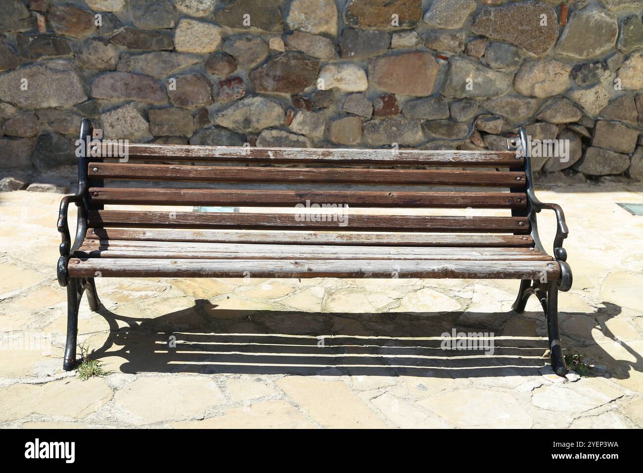 Banco vecchio sullo sfondo di un muro di pietra Foto Stock