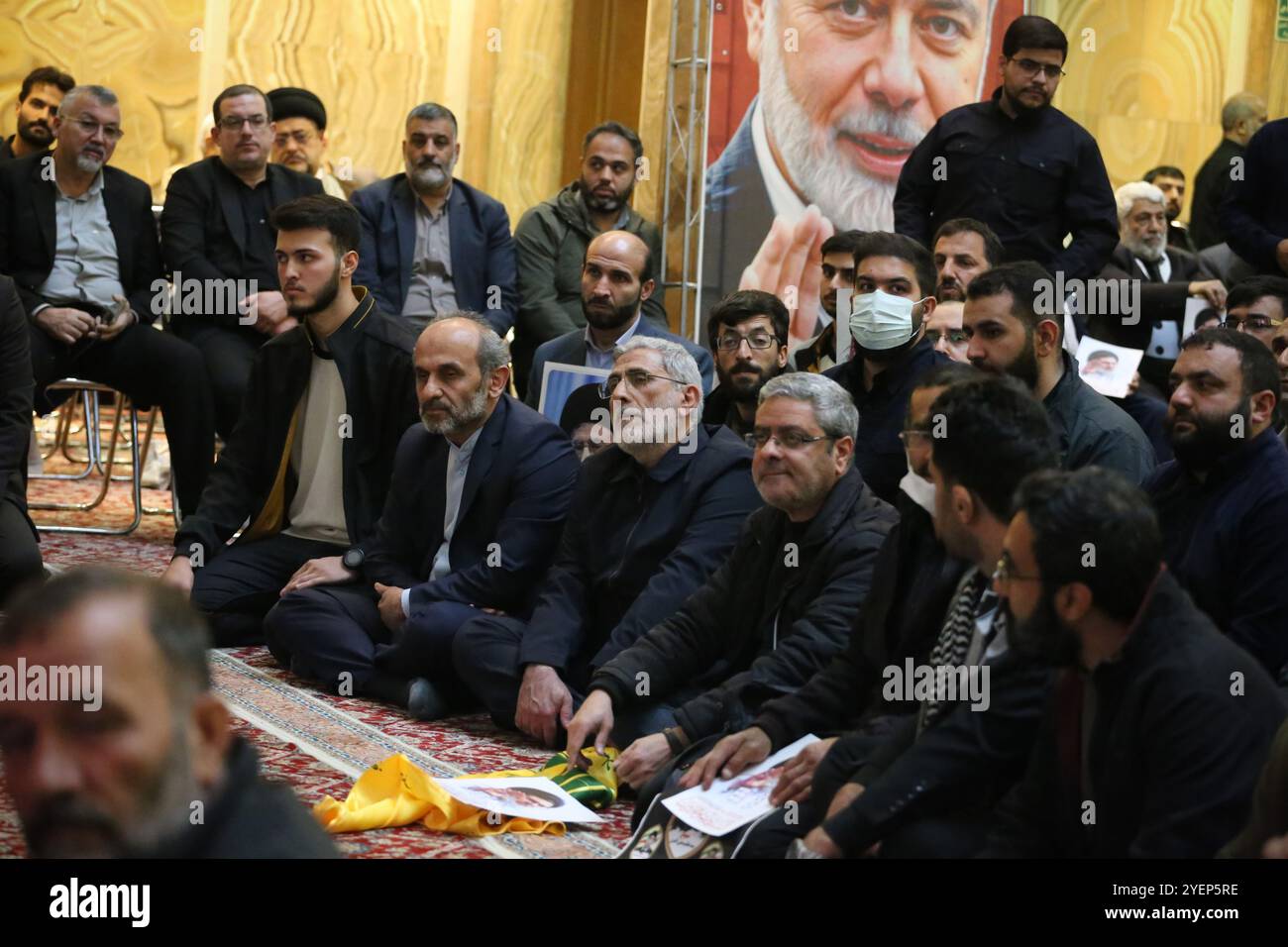 Teheran, Iran. 31 ottobre 2024. Il generale di brigata iraniano ESMAIL QAANI (C-Bottom), capo della forza Quds del corpo delle guardie rivoluzionarie islamiche (IRGC), siede di fronte al presidente ucciso dell'ufficio politico di Hamas, Yahya Sinwar, striscione durante una cerimonia in Piazza Palestina a Teheran, in commemorazione del defunto Hashem Safieddine, un importante chierico che doveva succedere al leader assassinato di Hezbollah Hassan Nasrallah, ucciso da un attacco israeliano a Beirut. Qaani, nominato dal leader supremo dopo la morte di Qasem Soleimani, guida le operazioni extraterritoriali della forza Quds Foto Stock